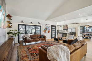 Living room featuring high vaulted ceiling, recessed lighting, an inviting chandelier, light wood finished floors, and baseboards