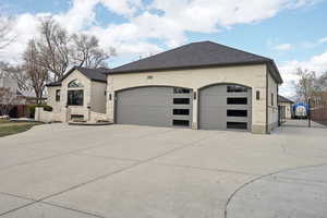 View of front facade with fence, driveway, roof with shingles, an attached garage, and brick siding