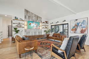 Living room featuring baseboards, beam ceiling, high vaulted ceiling, and light wood-style flooring