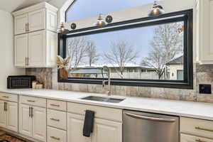 Kitchen featuring tasteful backsplash, a sink, white cabinetry, and stainless steel dishwasher