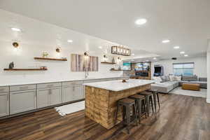 Kitchen featuring a center island, light countertops, gray cabinets, dark wood-style floors, and open shelves