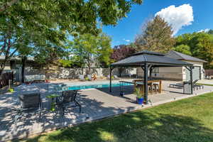 View of pool featuring a lawn, a deck, a fenced backyard, a gazebo, and a fenced in pool