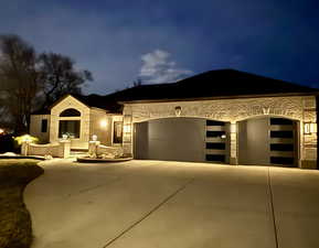 View of front of house with stone siding, an attached garage, and driveway