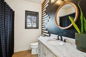 Bathroom with baseboards, toilet, wood finished floors, and vanity