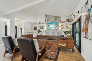 Living room with beamed ceiling, light wood-style flooring, and high vaulted ceiling