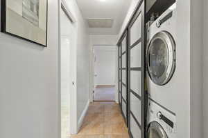 Clothes washing area featuring baseboards, stacked washer / dryer, laundry area, and visible vents