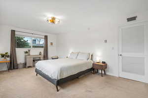 Bedroom with light colored carpet, visible vents, and baseboards