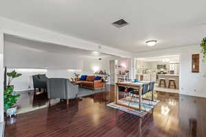 Living area with a chandelier, visible vents, baseboards, and wood finished floors