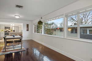 Dining space with dark wood finished floors, visible vents, an inviting chandelier, and baseboards