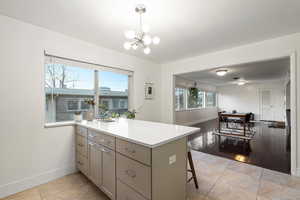 Kitchen with a peninsula, baseboards, light countertops, and an inviting chandelier