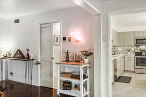 Hallway with light tile patterned floors, baseboards, and visible vents