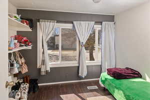 Bedroom featuring visible vents, baseboards, and wood finished floors