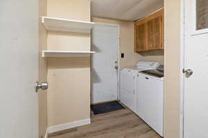 Clothes washing area featuring light wood finished floors and washer and clothes dryer