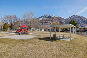 Community jungle gym with a yard, fence, and a mountain view