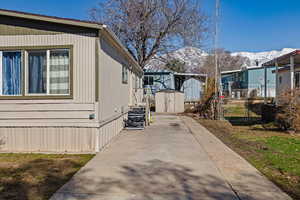 View of side of property featuring a mountain view, an outbuilding, a storage shed, and fence