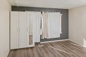 Unfurnished bedroom with visible vents, baseboards, and wood finished floors