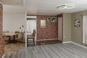 Dining area with visible vents, baseboards, wood finished floors, and brick wall