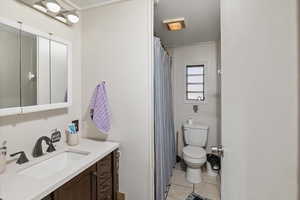 Bathroom featuring tile patterned flooring, a shower with shower curtain, toilet, and vanity