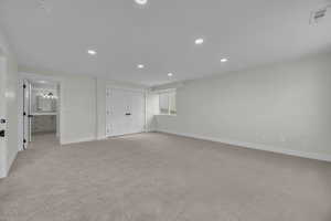 Interior space featuring light carpet, visible vents, recessed lighting, and baseboards