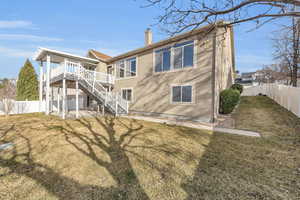 Back of house with stairway, a lawn, a chimney, and a fenced backyard