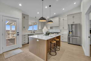 Kitchen with a kitchen island, a sink, stainless steel appliances, light countertops, and a kitchen bar