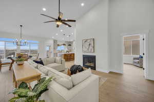 Living room featuring a glass covered fireplace, baseboards, light wood finished floors, and high vaulted ceiling