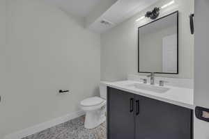 Bathroom featuring visible vents, toilet, vanity, and baseboards