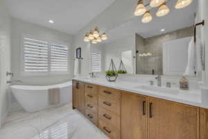 Bathroom featuring a freestanding bath, double vanity, a stall shower, marble finish floor, and a sink