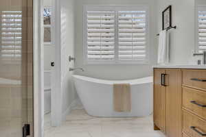 Full bathroom featuring marble finish floor, toilet, and a freestanding tub