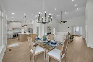 Dining space featuring visible vents, light wood-style flooring, a fireplace, and high vaulted ceiling