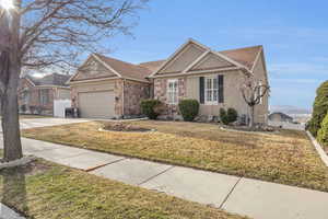 View of front facade featuring a garage, driveway, a front lawn, and fence