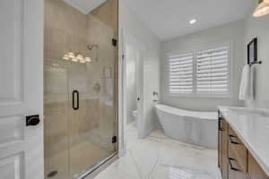 Bathroom featuring a shower stall, recessed lighting, a soaking tub, marble finish floor, and vanity