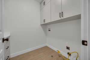 Laundry room with hookup for a washing machine, baseboards, hookup for an electric dryer, cabinet space, and light wood-type flooring