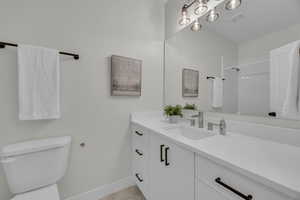 Bathroom featuring visible vents, walk in shower, baseboards, toilet, and vanity