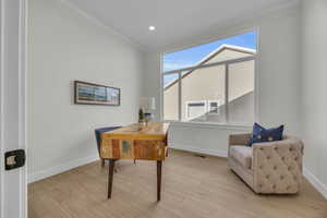 Home office with visible vents, crown molding, light wood-type flooring, and baseboards