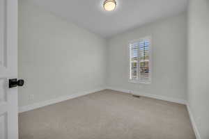 Carpeted spare room featuring visible vents and baseboards