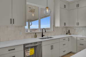 Kitchen featuring a sink, decorative backsplash, hanging light fixtures, light countertops, and dishwasher