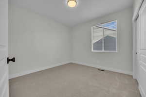 Unfurnished bedroom featuring light colored carpet, visible vents, and baseboards