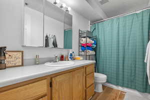 Bathroom featuring visible vents, toilet, wood finished floors, and vanity