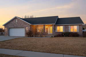 Ranch-style home with brick siding, an attached garage, concrete driveway, and a yard