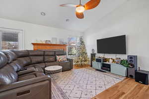 Living area featuring lofted ceiling, a ceiling fan, and light wood finished floors