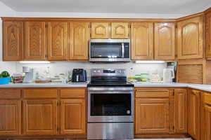 Kitchen with brown cabinets, appliances with stainless steel finishes, and light countertops