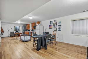 Dining room featuring light wood-style floors, baseboards, and a textured ceiling