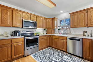 Kitchen featuring a sink, light countertops, brown cabinetry, and stainless steel appliances