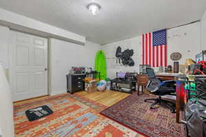 Office with wood finished floors and a textured ceiling