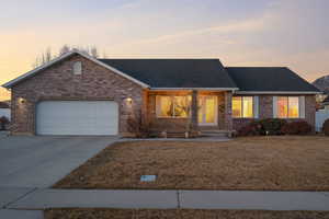 Ranch-style house with roof with shingles, an attached garage, concrete driveway, a lawn, and brick siding