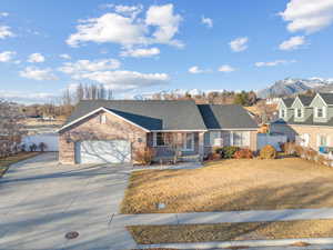 Ranch-style house featuring fence, a mountain view, concrete driveway, a garage, and brick siding