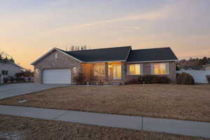 Ranch-style house with a front yard, fence, concrete driveway, a garage, and brick siding
