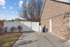View of property exterior with a gate, fence, and brick siding