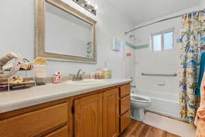 Bathroom with vanity, toilet, wood finished floors, and shower / tub combo with curtain